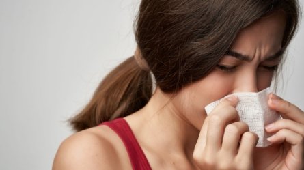 A young woman suffering from the symptoms of common cold.